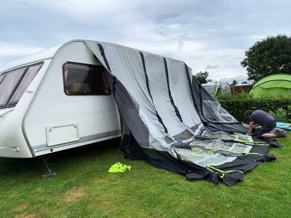 Medewerker van Caravanverhuur Spanje zet een voortent professioneel op bij een caravan op een Spaanse camping